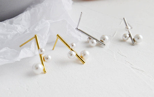 Gold and silver earrings with pearls on a light background
